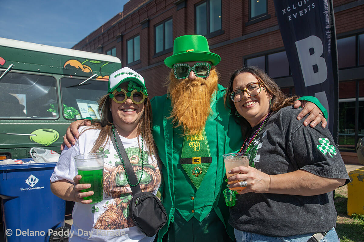 A man dressed as a leprechaun poses with two women.